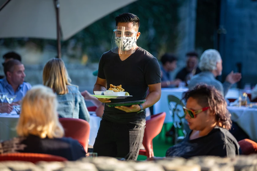 Server wearing a mask and faceshield as they serve customers outside in the streets of Los Angeles.