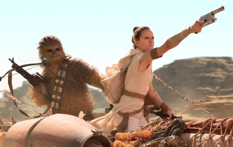 Screenshot of a star wars movie still. shows Rey and Chewie on a bike.